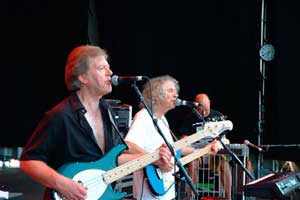 two men on stage singing and playing electric guitar